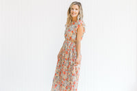 Model wearing a mint midi dress with a floral pattern, ruffle capped sleeve and a pleated skirt. 