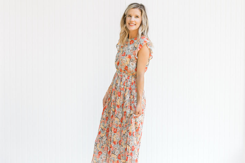 Model wearing a mint midi dress with a floral pattern, ruffle capped sleeve and a pleated skirt. 