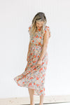 Model wearing a mint dress with a salmon, taupe and cream floral pattern with ruffle capped sleeve.