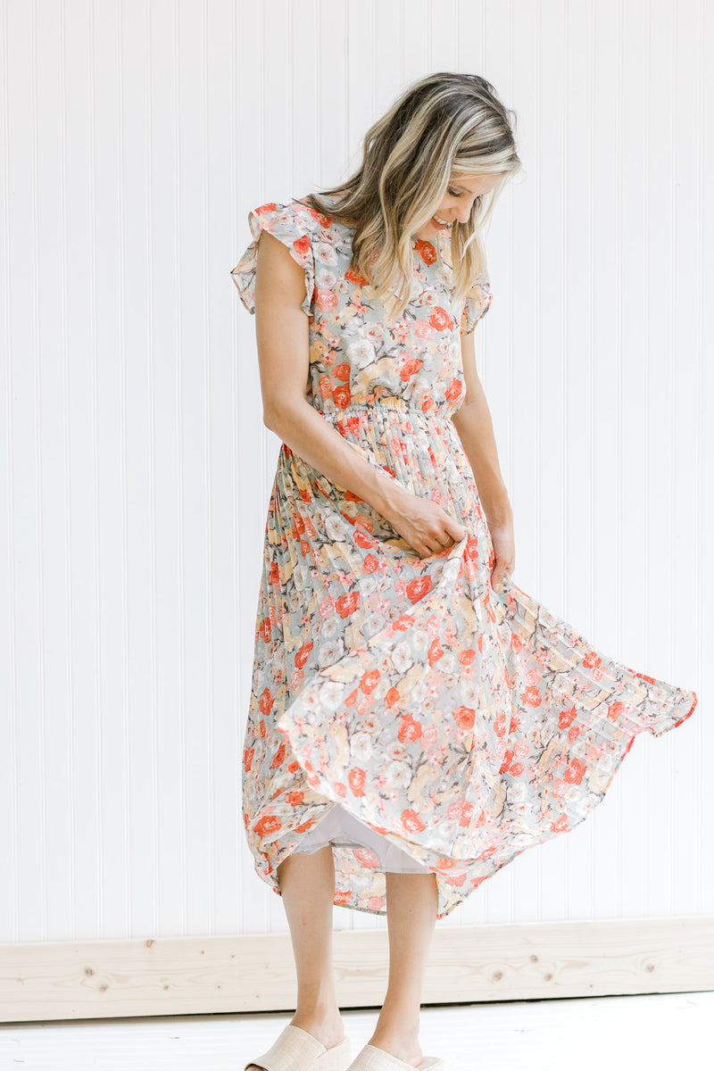 Model twirling in a mint dress with a floral pattern, ruffle capped sleeves and a pleated skirt. 