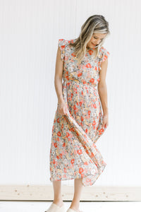Model wearing a mint dress with a floral pattern, an elastic waistband and ruffle capped sleeves. 