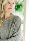 Close up of three button closure on a mint knit sweater with long sleeves and a round neck.