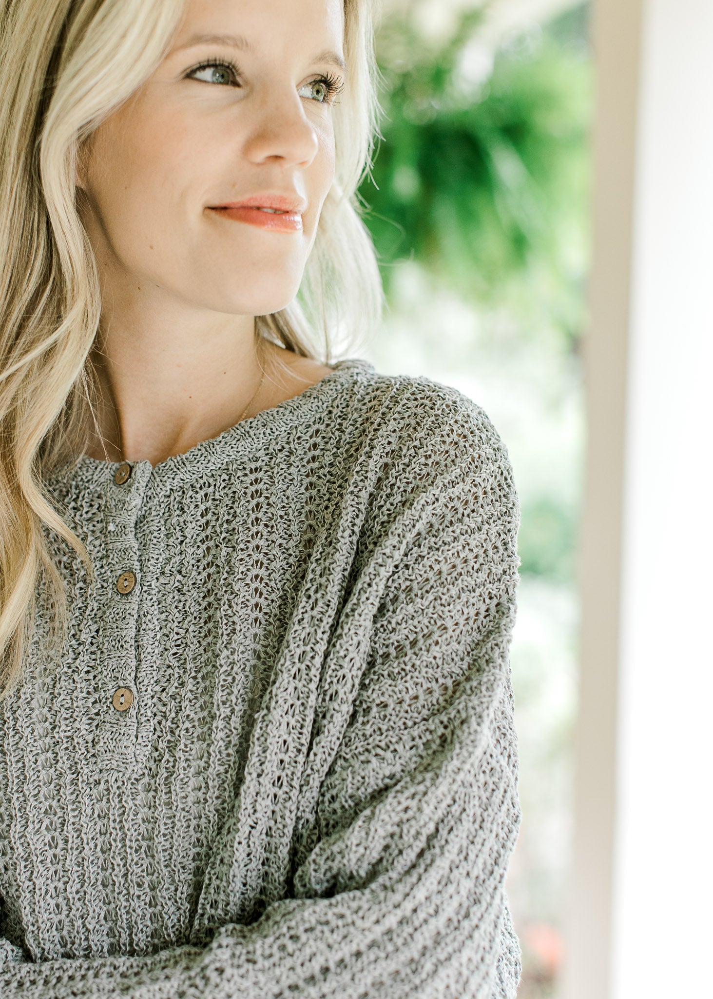 Close up of three button closure on a mint knit sweater with long sleeves and a round neck.