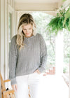 Model wearing white pants with a mint knit sweater with long sleeves and three button closure.  