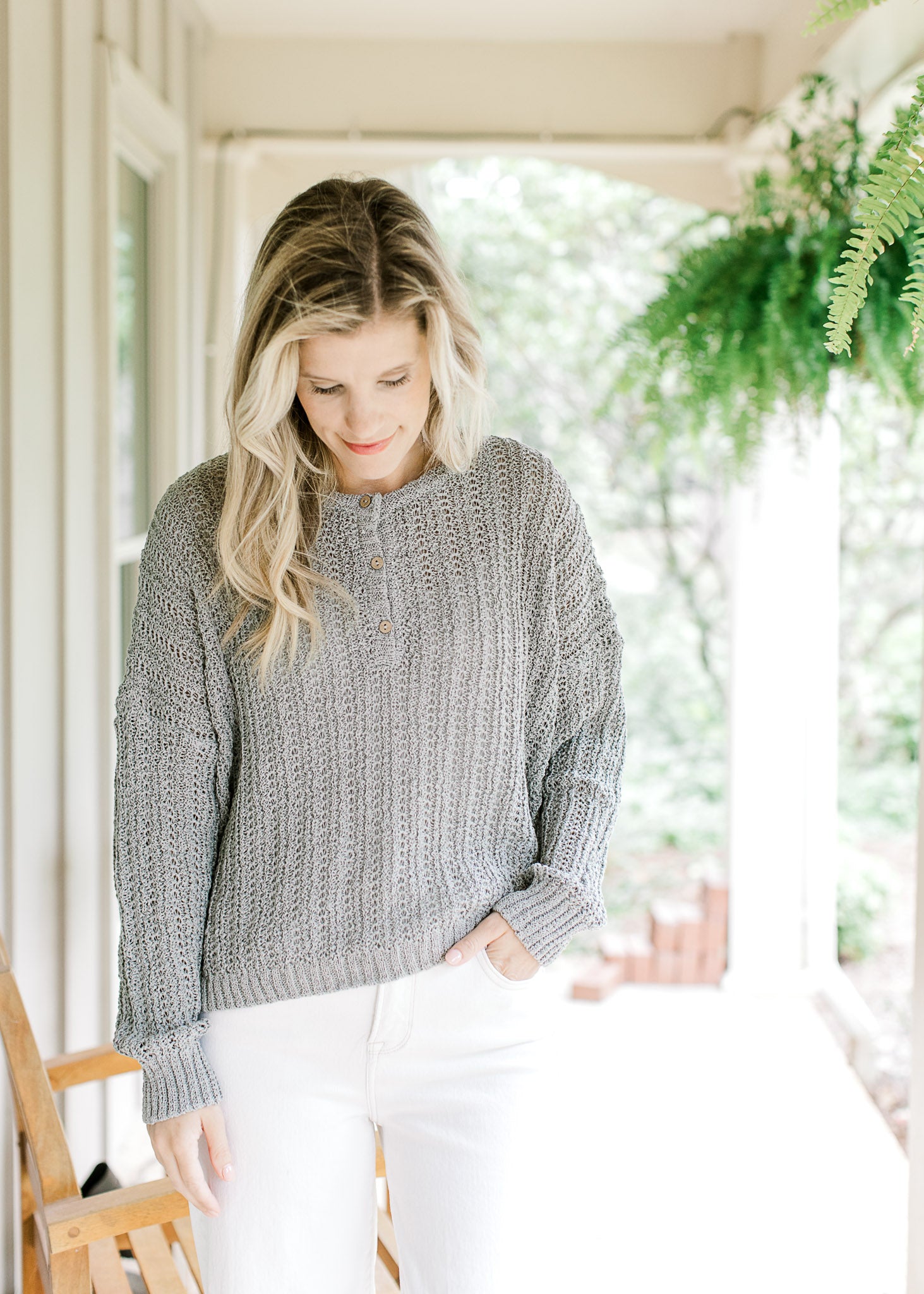 Model wearing white pants with a mint knit sweater with long sleeves and three button closure.  