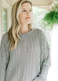Model wearing a loose fit mint knit sweater with long sleeves and three button closure.  