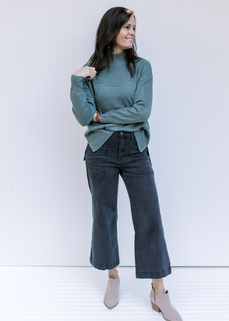 Model wearing a sage long sleeve top with a knit yolk detail and a mock neckline. 