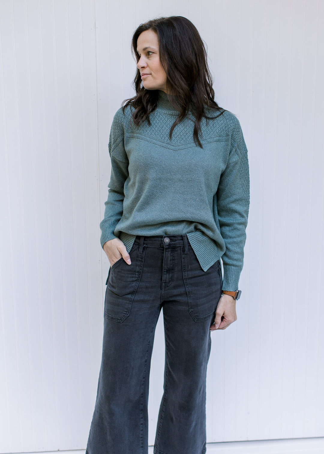 Model wearing jeans with a sage long sleeve top with a knit yolk detail and a mock neckline. 