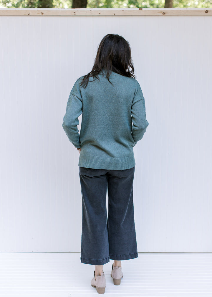 Back view of Model wearing a sage long sleeve top with a knit yolk detail and a mock neckline. 