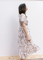 Side view of Model wearing a cream midi with gray floral, smocked bodice and bubble short sleeves.