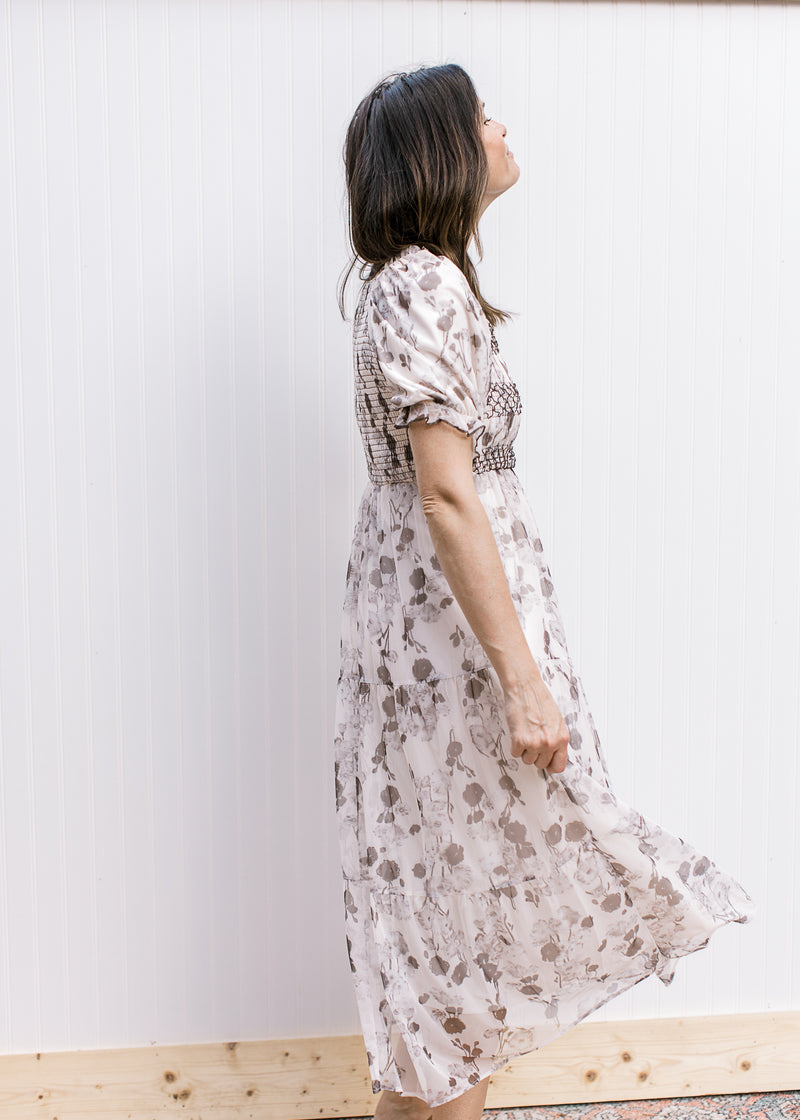 Side view of Model wearing a cream midi with gray floral, smocked bodice and bubble short sleeves.