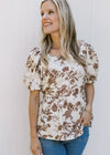 Model wearing a peplum white top with mocha floral a square neck and bubble short sleeves.