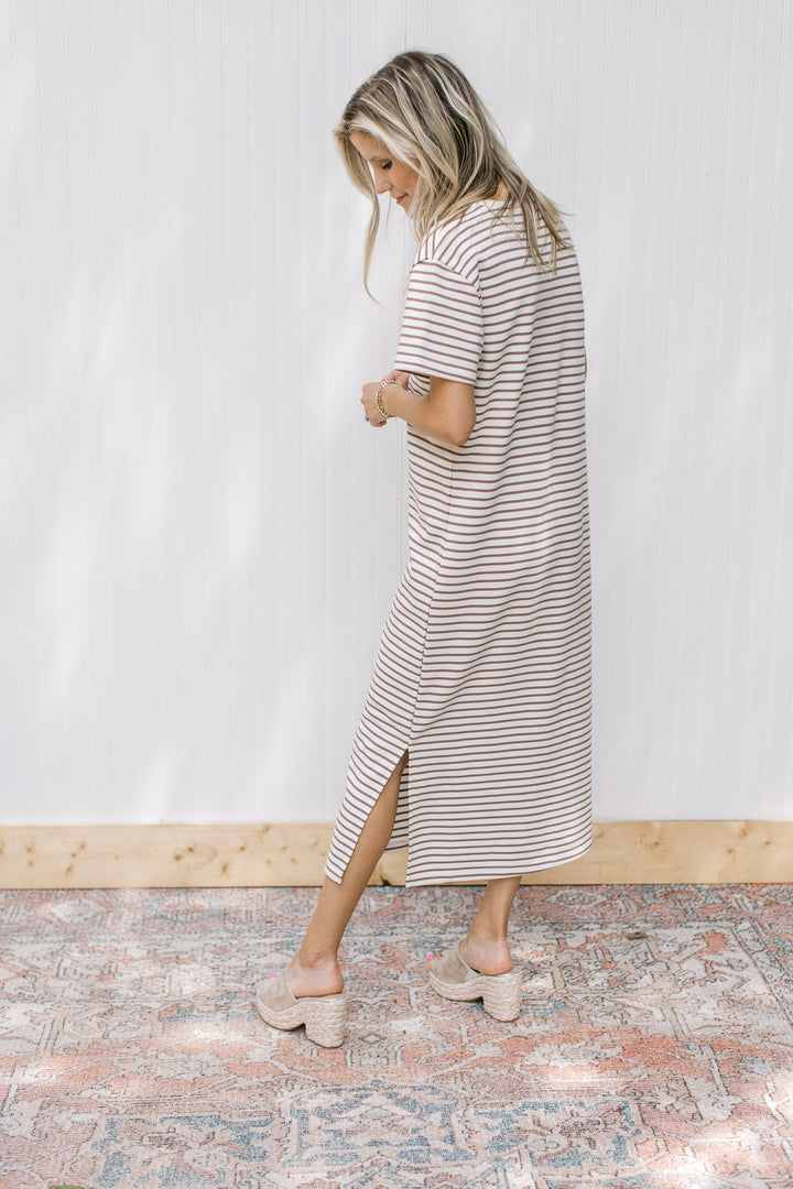 Model wearing a white midi with mocha stripes, short sleeves, side slits and a round neck.
