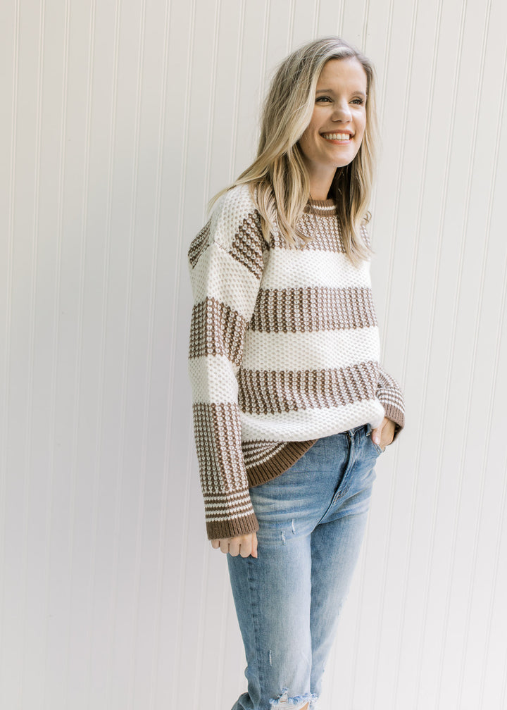 Model wearing a mocha and white striped sweater with a textured knit, round neck and long sleeves. 