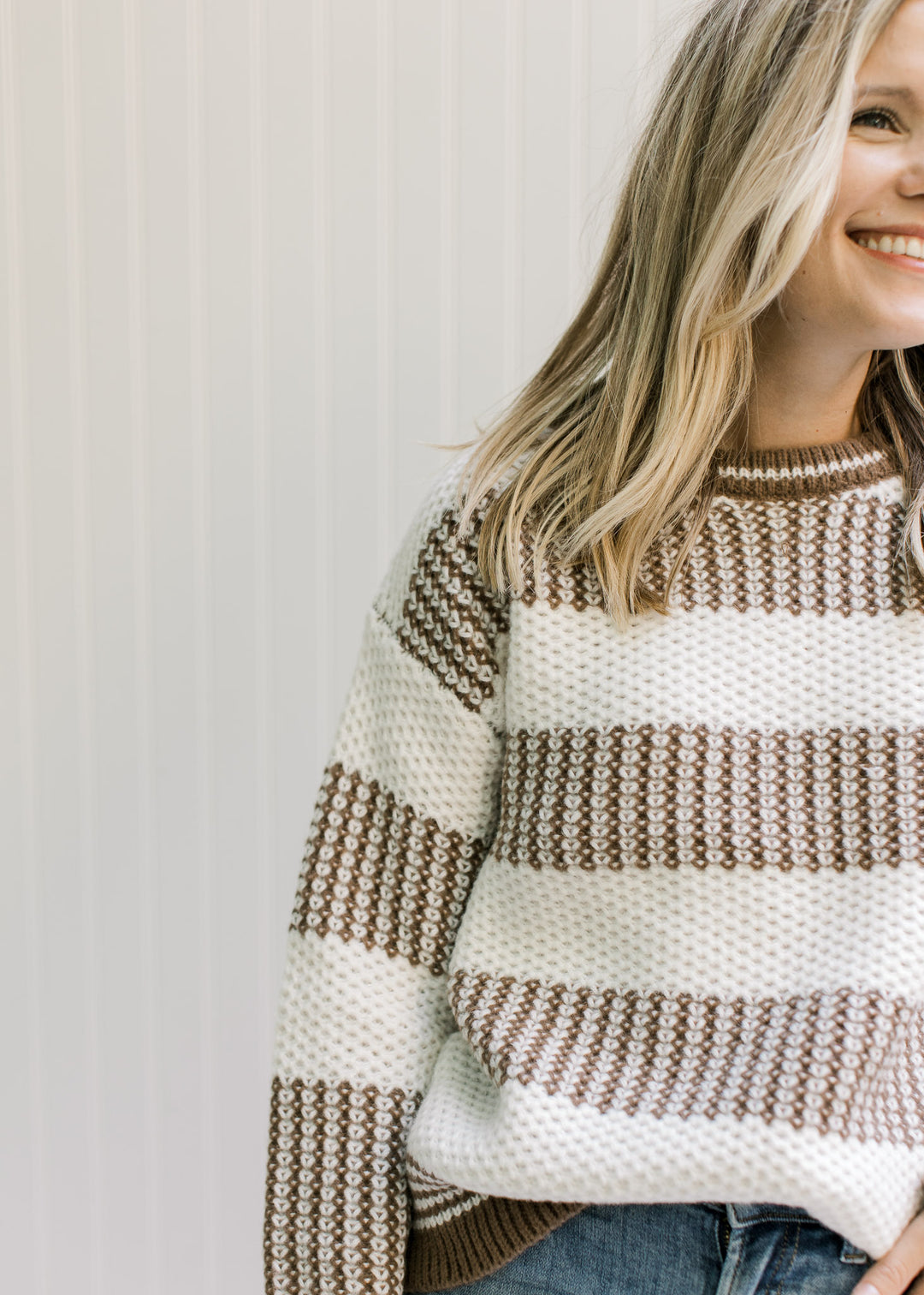Close up of textured knit on a mocha and white sweater with a crew neck and long sleeves. 