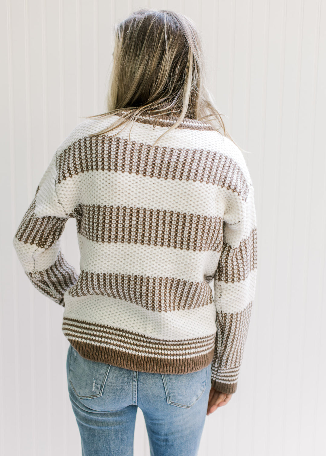 Back view of Model wearing a mocha and white striped sweater with a textured knit and long sleeves. 