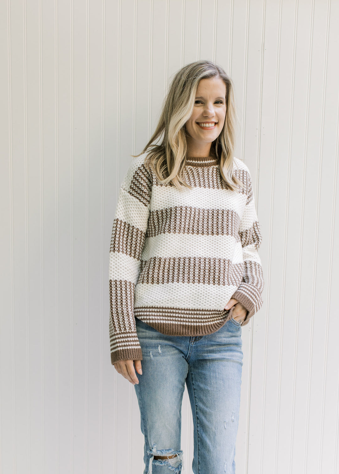 Model wearing a texture mocha and white striped sweater with a round neck and long sleeves. 