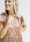 Close up of v-neck and flutter cap sleeves on a mocha dress with a blush floral pattern. 