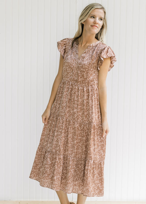 Model wearing a mocha, v-neck, tiered midi with a blush floral pattern and flutter cap sleeves. 
