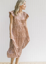 Model wearing a mocha, tiered midi with a blush floral pattern and flutter cap sleeves.