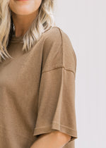 Close up view of exposed detail on short sleeve of a mocha colored top. 