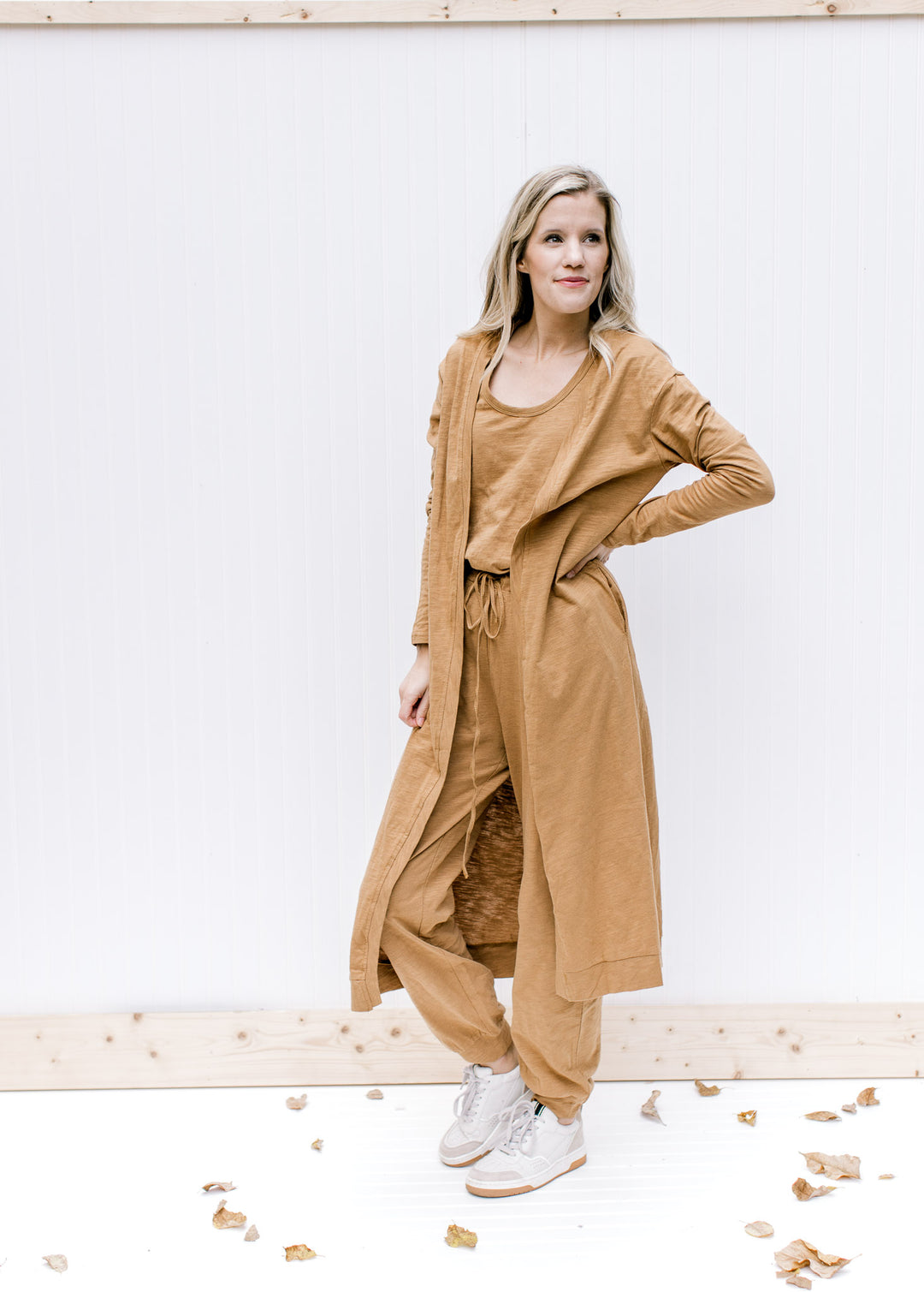 Model wearing a sleeveless mocha jumpsuit with a long matching cardigan with long sleeves. 
