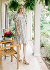 Model wearing wedges and a cream short sleeve dress with mocha floral and square neck.