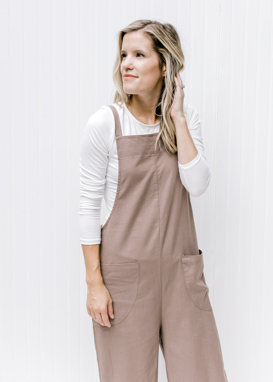 Model wearing a mocha jumpsuit with a square neckline, wide legs and adjustable straps. 