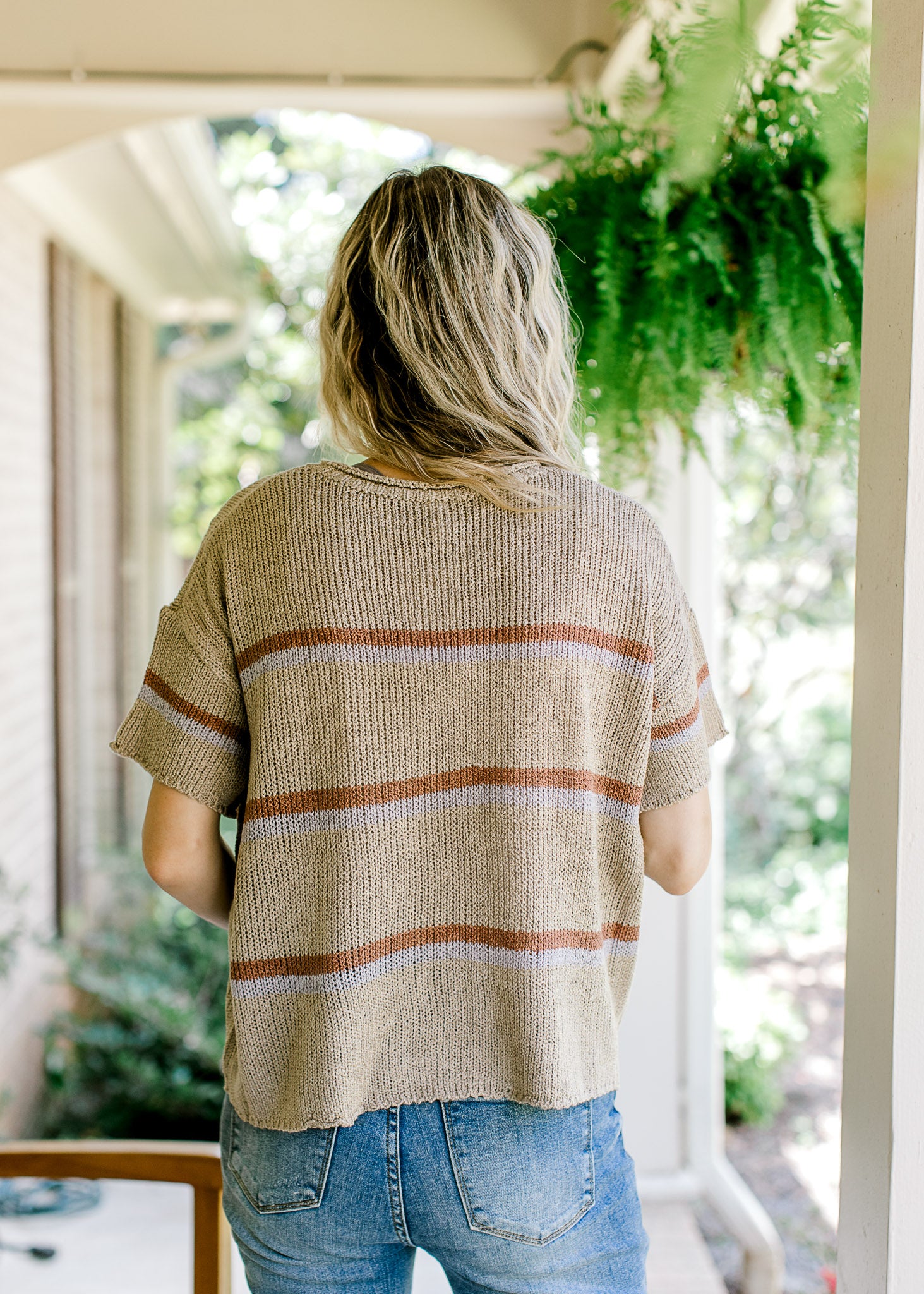 Back view of taupe woven top with short sleeves and brown and gray stripes. 