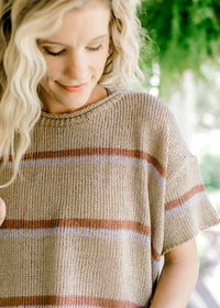 Close up of ribbed woven taupe top with brown and gray stripes and short sleeves.