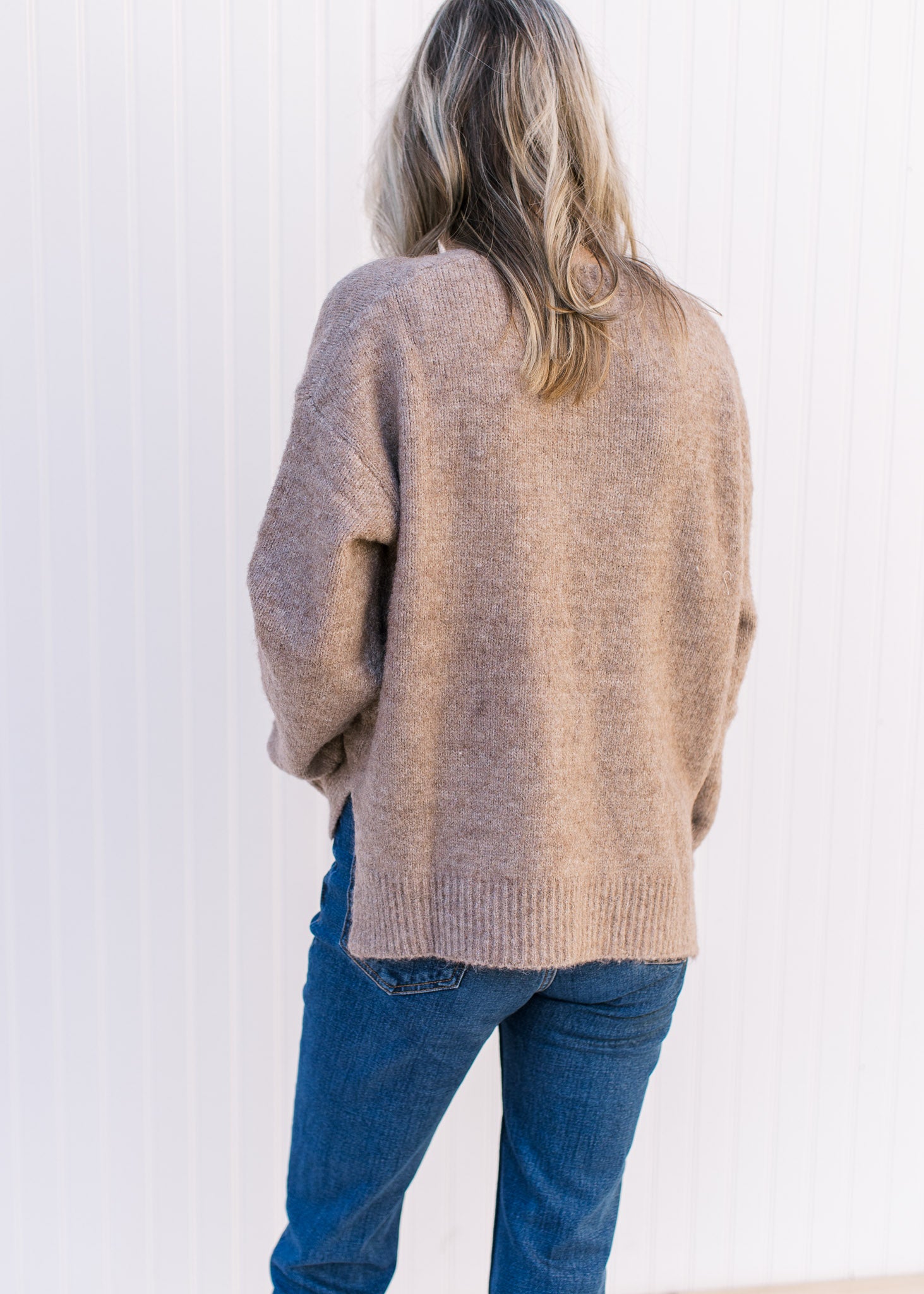 Back view of Model wearing a taupe sweater with ribbed detailing, a round neck and long sleeves.