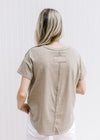 Back view of Model wearing a mocha colored tee with a raw hemline, round neck and short sleeves. 