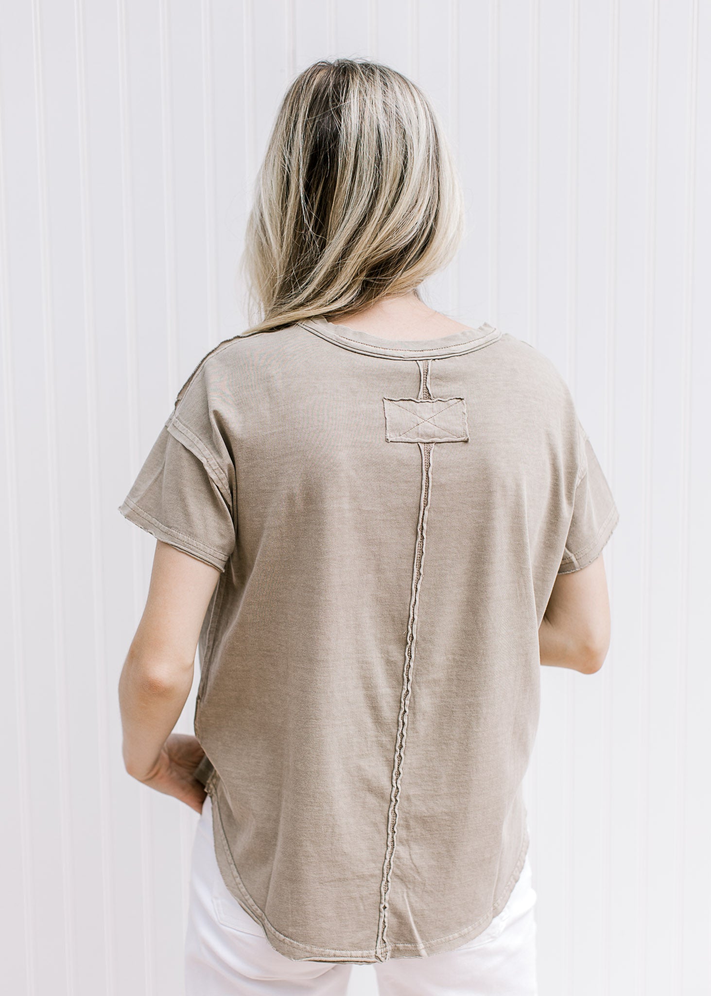 Back view of Model wearing a mocha colored tee with a raw hemline, round neck and short sleeves. 
