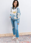 Model wearing jeans, sneakers and a pale blue long sleeve sweater with cream and yellow floral.