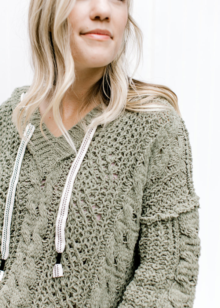 Close up of woven white string detail on the hood of a moss colored hoodie with long sleeves. 