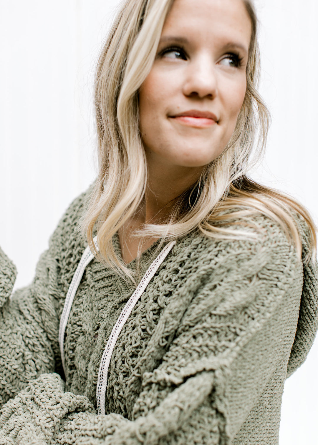 Close up of woven detail and exposed hem on a moss colored hood I with long sleeves. 