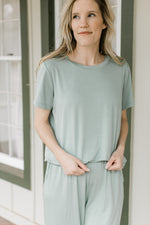 Model wearing a mossy green matching set with a short sleeve crew top and wide leg bottoms.