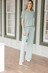 Model wearing a moss colored set with a short sleeve crew neck top and wide leg bottoms. 