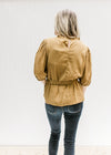 Back view of Model wearing a copper colored top with a ruffled neckline, short sleeves and tie waist