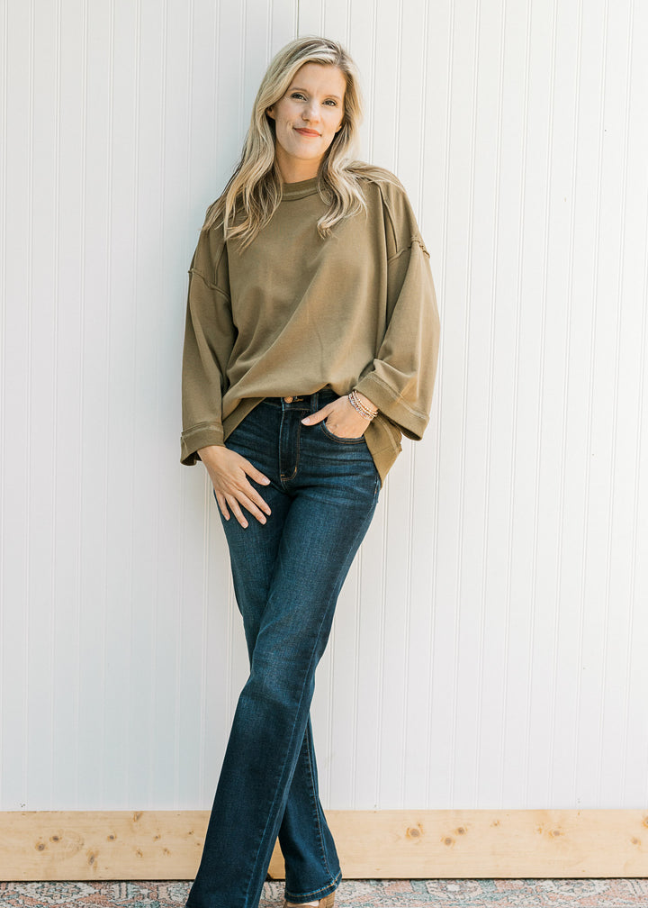 Model wearing an olive 3/4 sleeve top with a round neck, exposed hem and patch with seam along back.