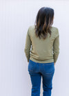 Back view of Model wearing a lightweight olive green sweater with long sleeves and a mock neck. 