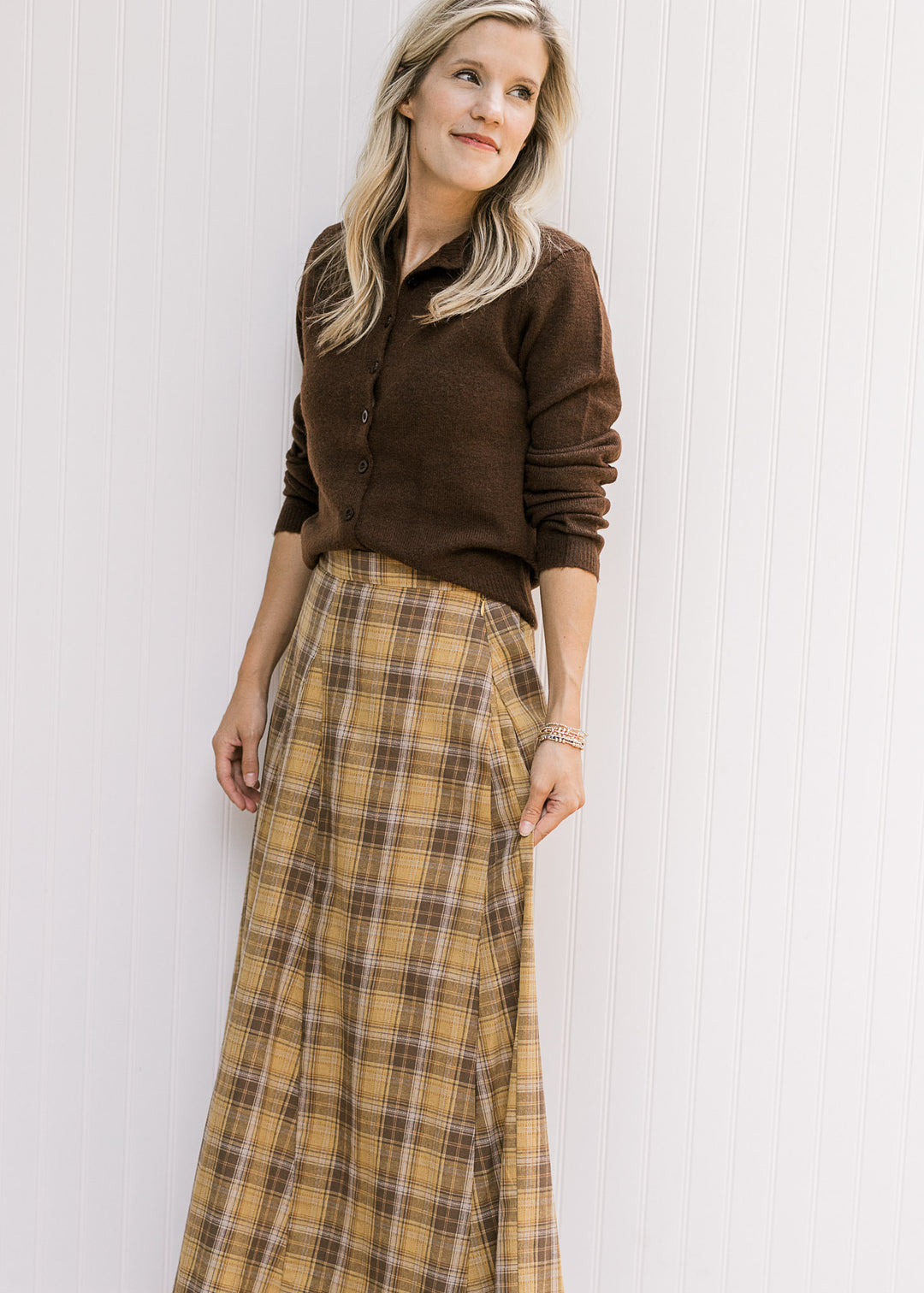 Model wearing a gold and brown plaid midi with gored side panels, elastic in back and side zipper. 