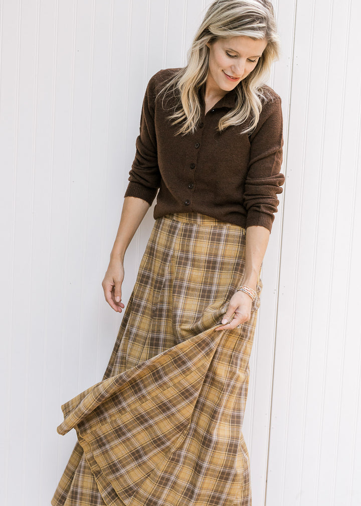Model showing gored side panels on a gold and brown plaid midi with elastic back and side zipper. 
