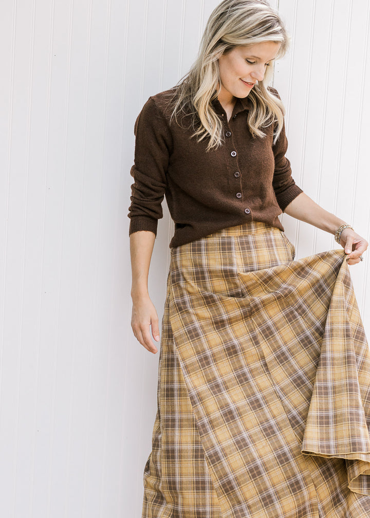 Model wearing brown sweater with a gold and brown plaid midi with gored side panels. 
