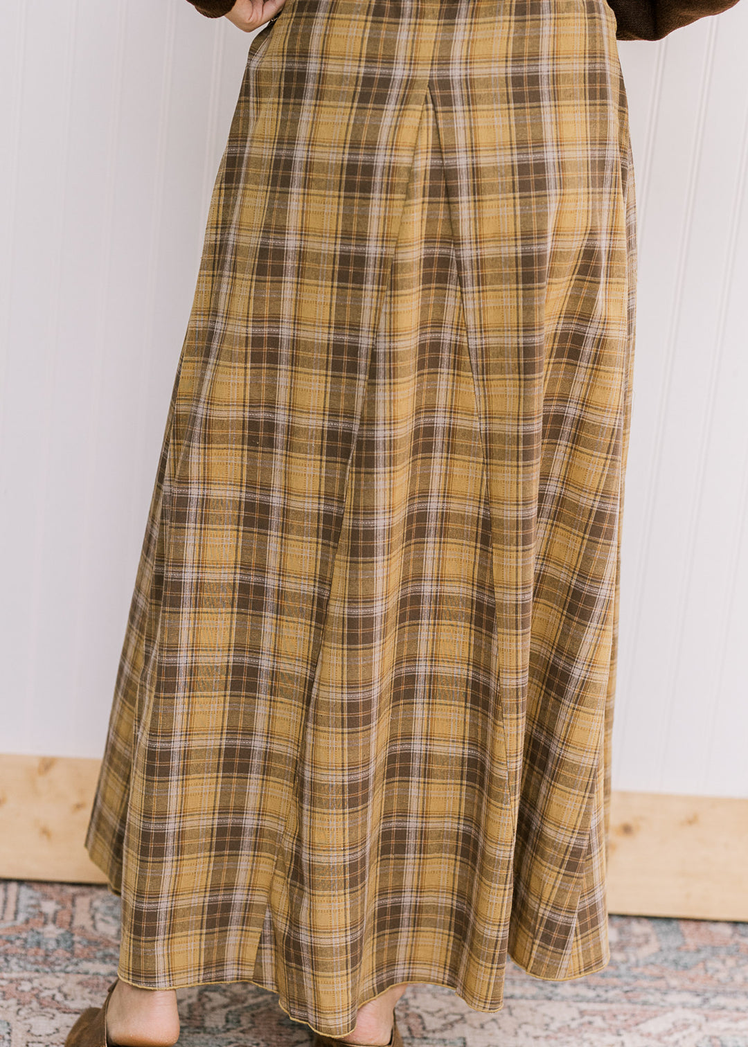 Back view of Model wearing a gold and brown plaid midi with gored side panels and side zipper. 