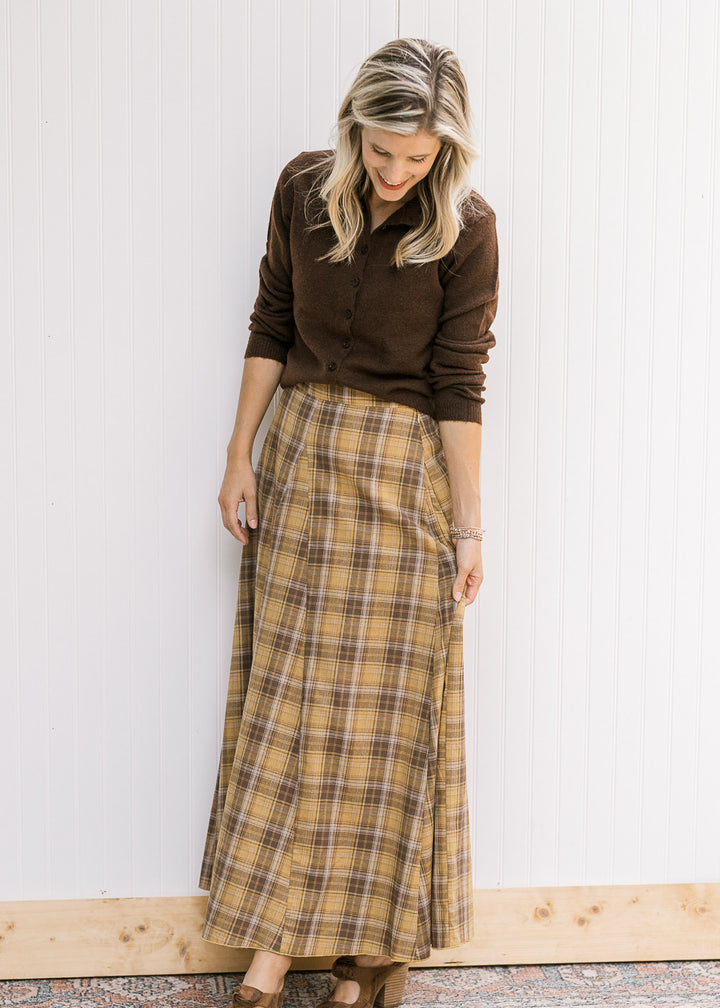 Model wearing a brown sweater, heels and a gold and brown plaid midi with gored side panels. 