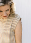 Close up of capped sleeve on the top of a cream and yellow striped top with matching pants.