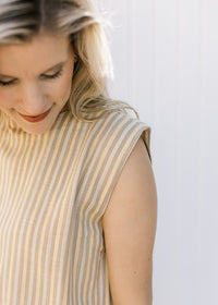 Close up of capped sleeve on the top of a cream and yellow striped top with matching pants.