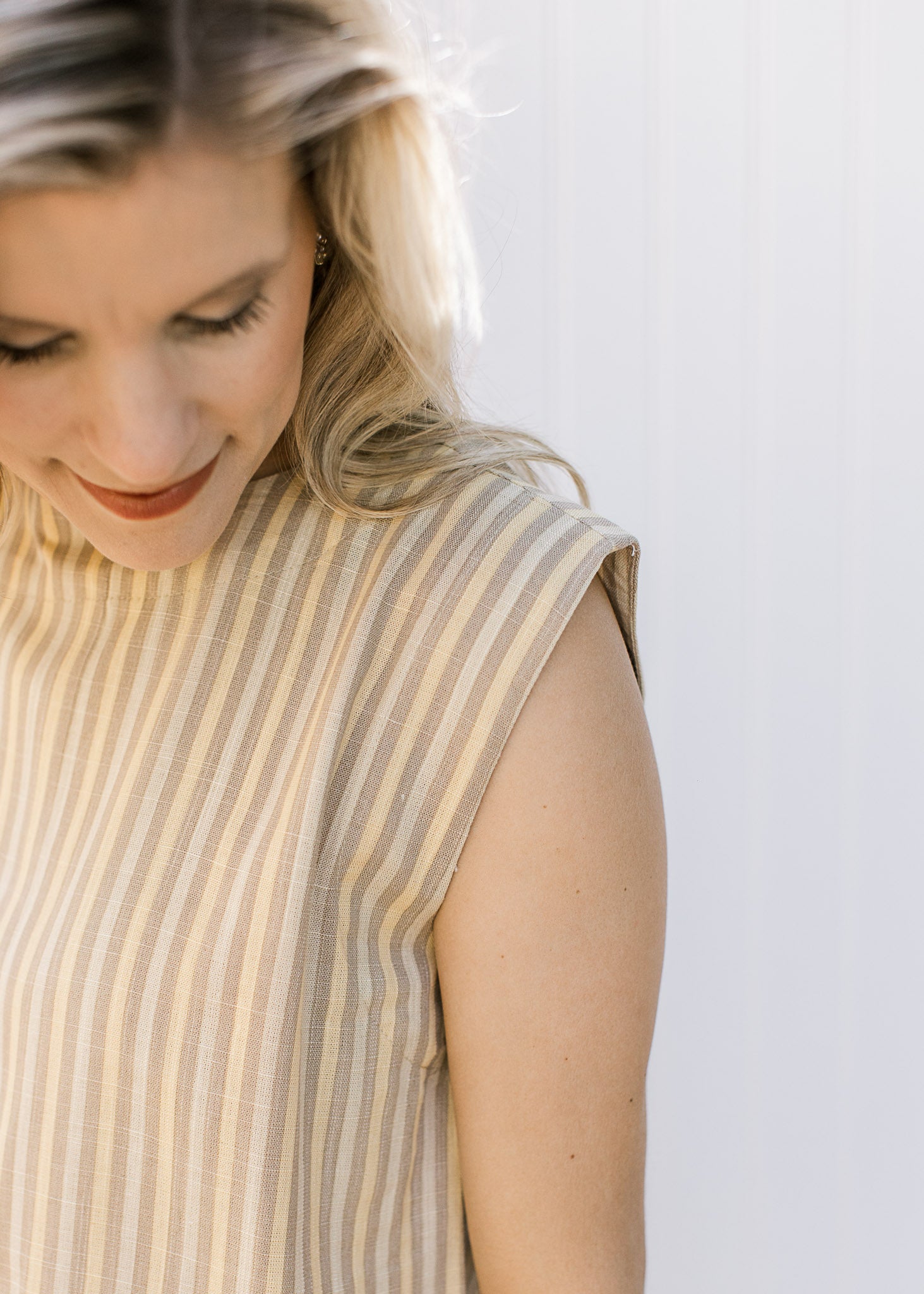 Close up of capped sleeve on the top of a cream and yellow striped top with matching pants.