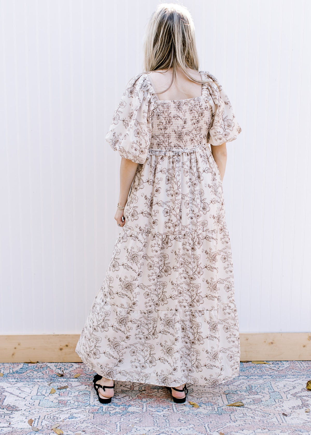 Back view of a cream short sleeve dress with brown floral, square neck and smocked bodice. 